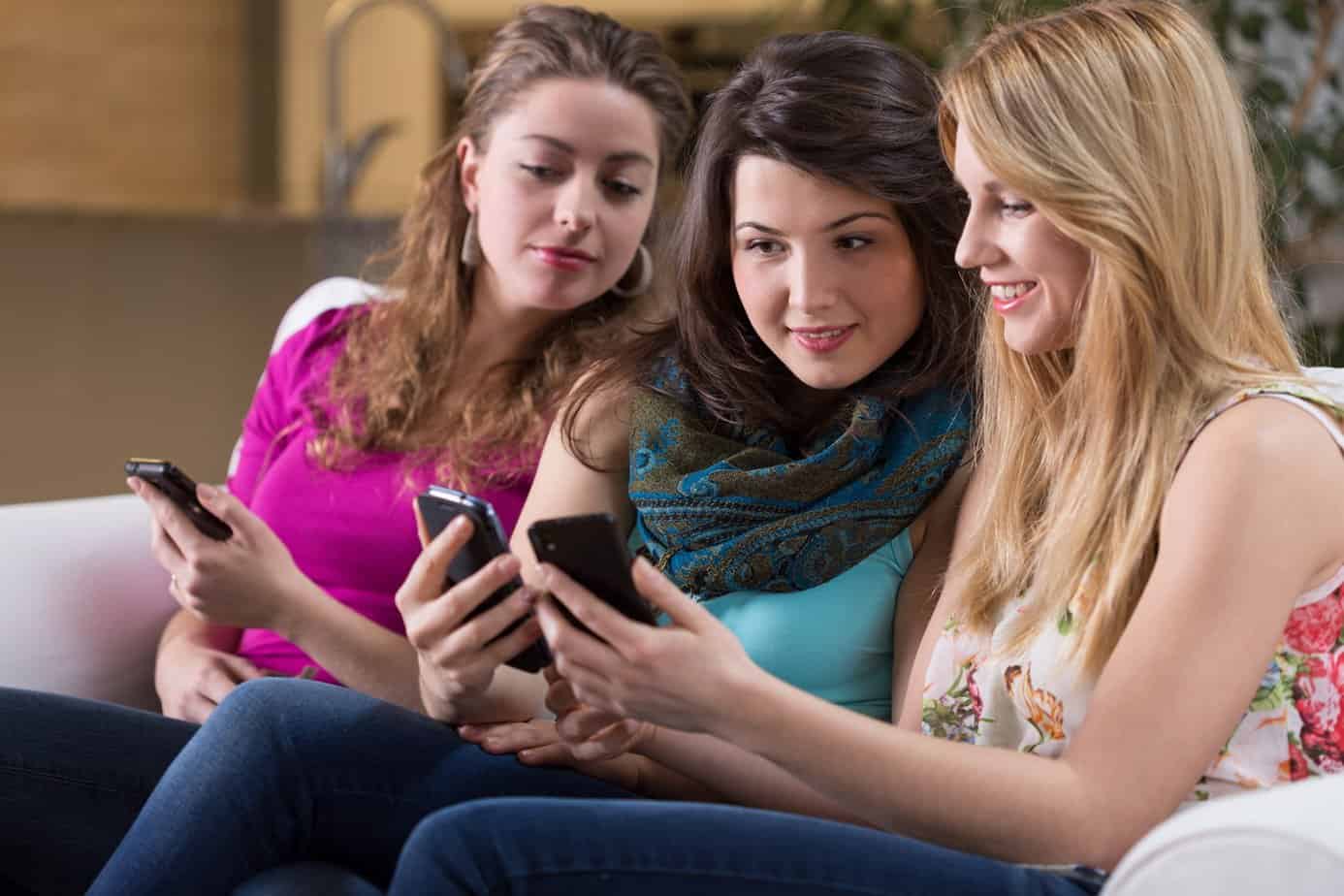 three girls looking at smartphones